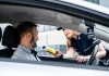 Policjantka podaje kierowcy alkomat do badania trzeźwości w aucie.